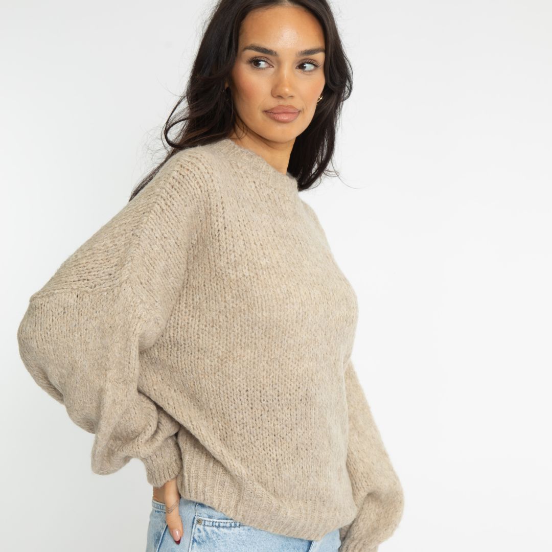 Woman wearing a beige sweater against a white background