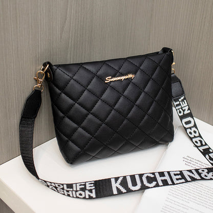 Black quilted handbag with a strap on a wooden surface