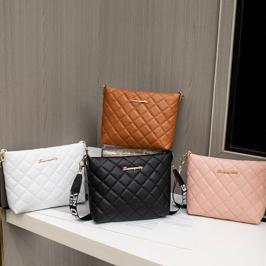Four quilted handbags in brown, white, black, and pink on a wooden surface with a gray wall background.