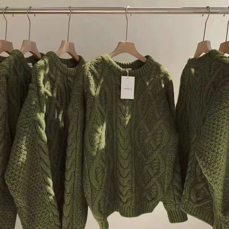 Green sweaters on hangers with a plain background
