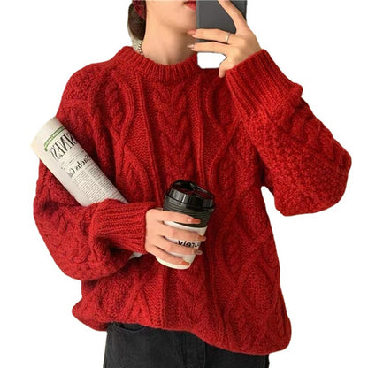 Person wearing a red sweater holding a coffee cup and a newspaper.