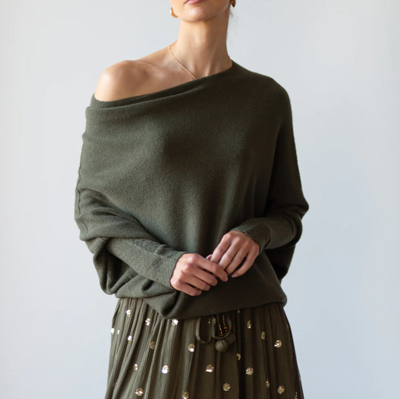 Person wearing an off-shoulder green sweater with a plain background