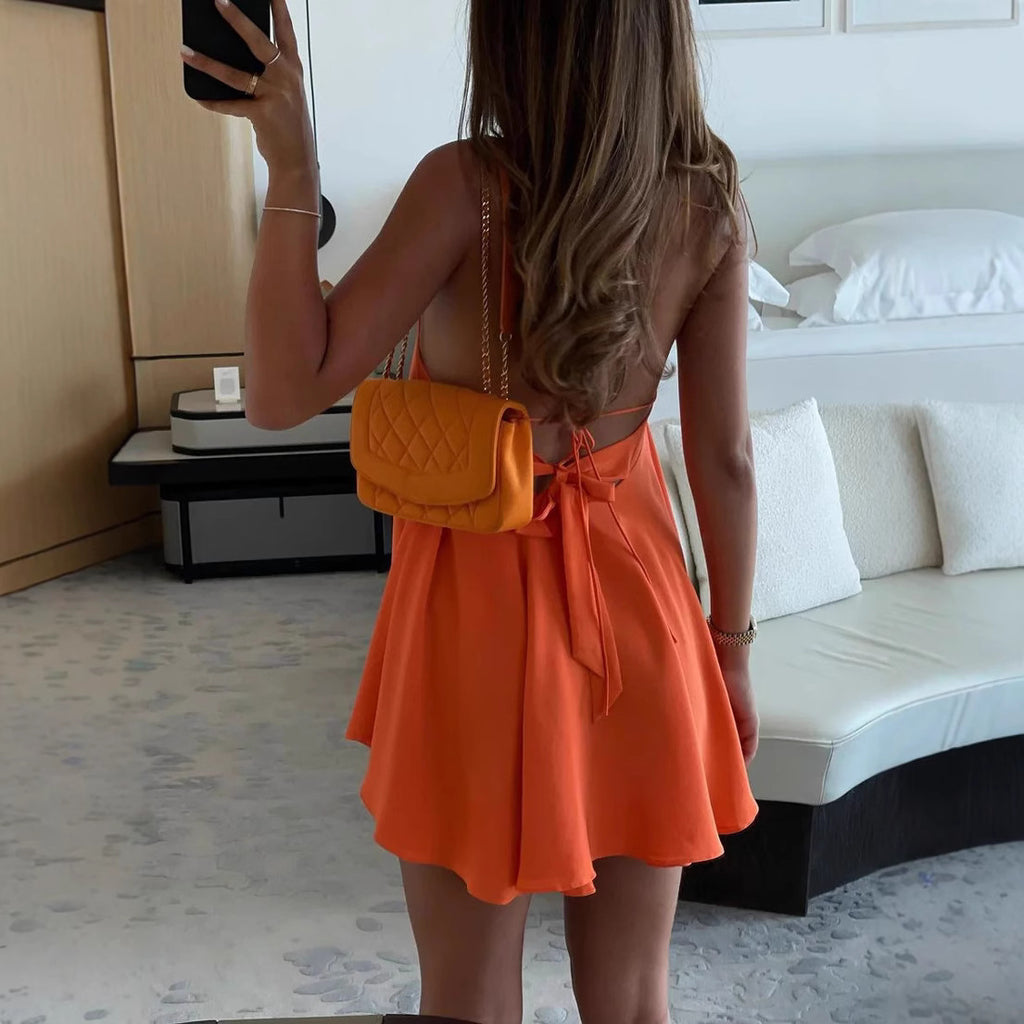 Person wearing an orange dress and yellow handbag in a bedroom setting