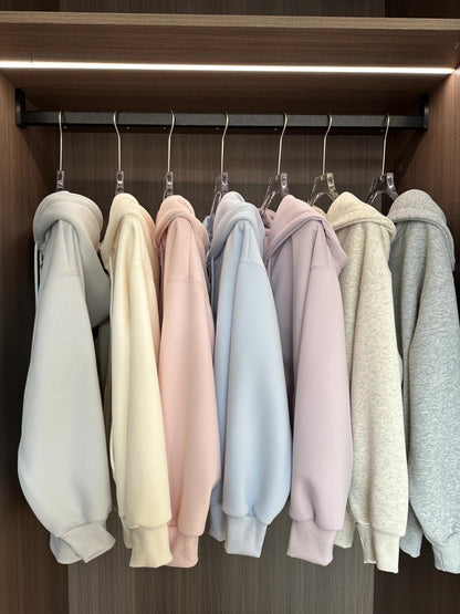 Row of pastel-colored hoodies hanging on a rack in a wardrobe.