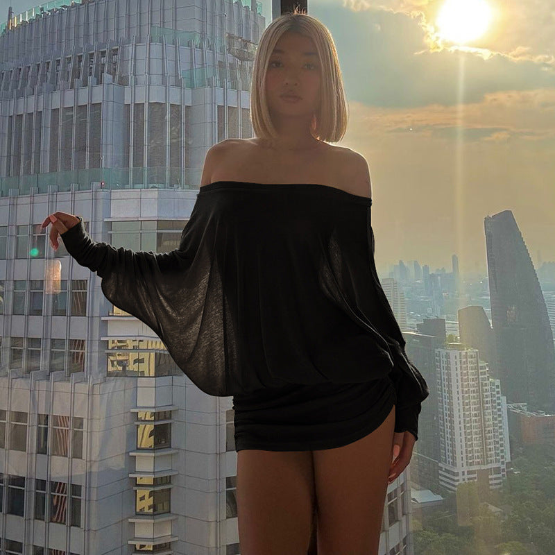 Woman in a black off-shoulder top and shorts standing in front of a city skyline with a sunset.