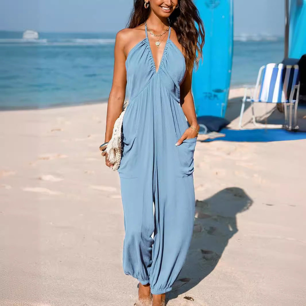 Woman in a blue dress standing on a beach with ocean and chairs in the background