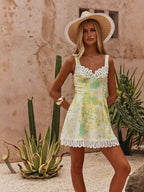 Woman in a floral dress and sun hat standing in front of a cactus plant.