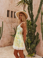 Woman in a floral dress and sun hat standing in front of cacti.