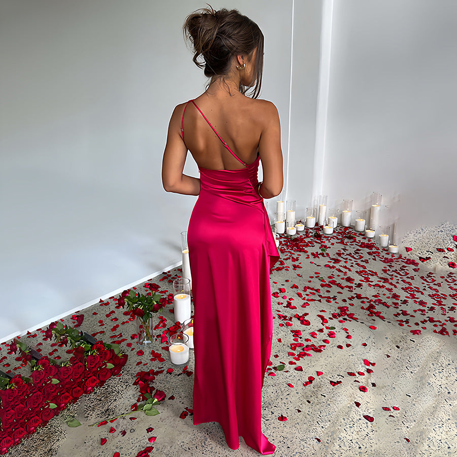 Woman in a pink dress standing in a room with candles and rose petals.