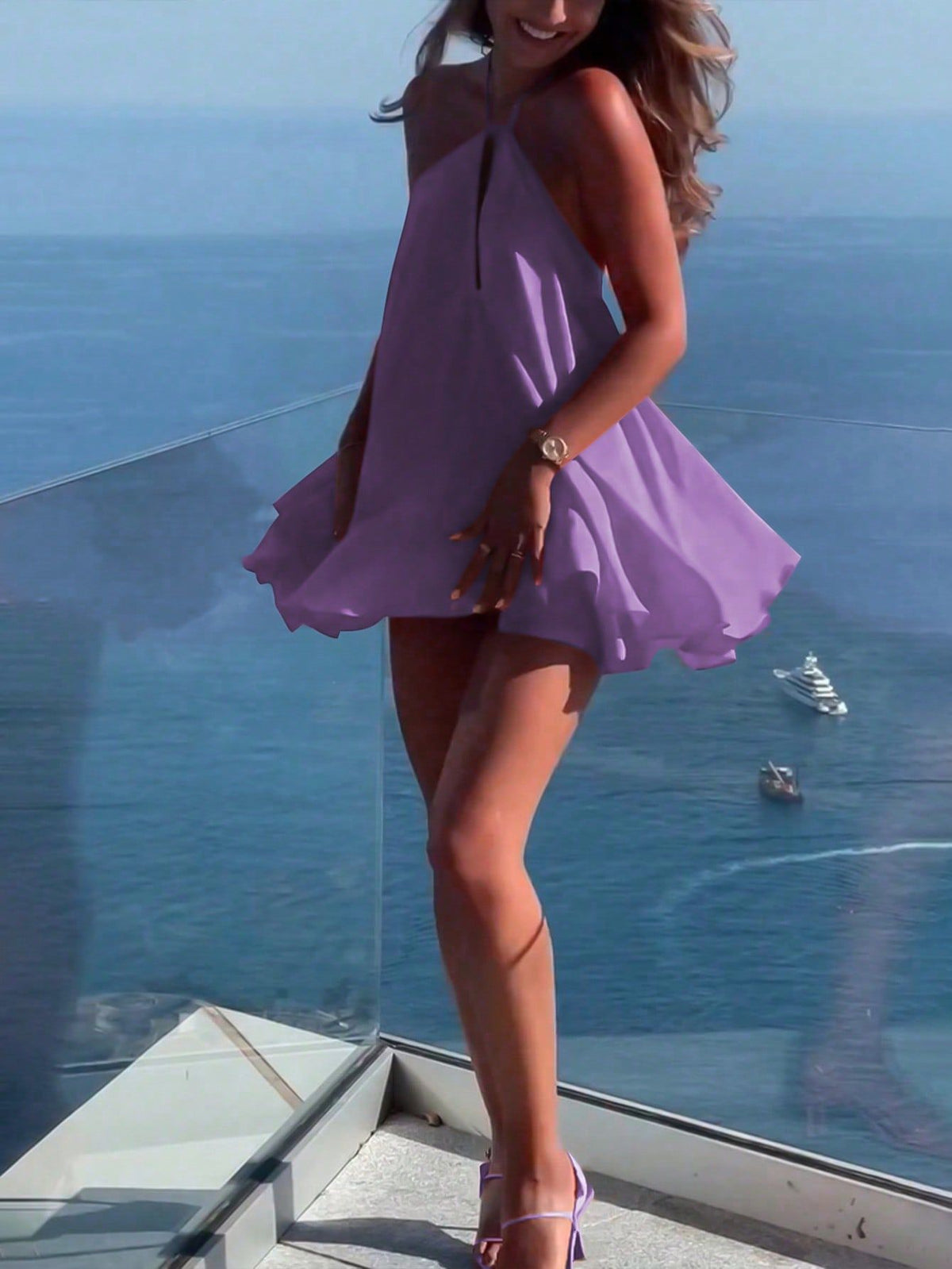 Woman in a purple dress standing on a balcony with a blue ocean view.