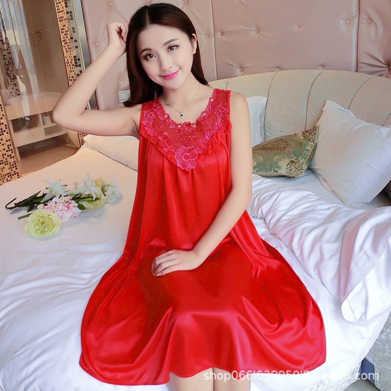 Woman in a red satin nightgown sitting on a bed with flowers and pillows.