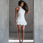 Woman in a white polka dot dress standing in a concrete hallway