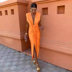 Woman in an orange dress standing against a terracotta-colored wall.