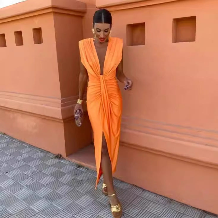 Woman in an orange dress standing against a terracotta-colored wall.