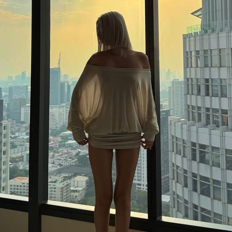 Woman standing by a window with a cityscape view during sunset.