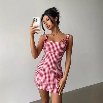 Woman taking a selfie wearing a red and white checkered dress against a plain background