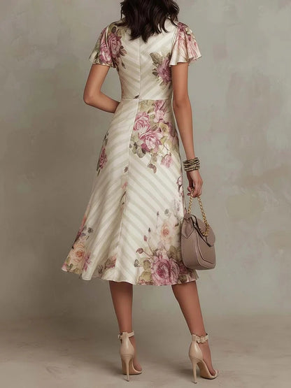 Woman wearing a floral dress with a beige handbag against a neutral background