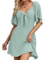 Woman wearing a light green dress with a tie detail on a white background