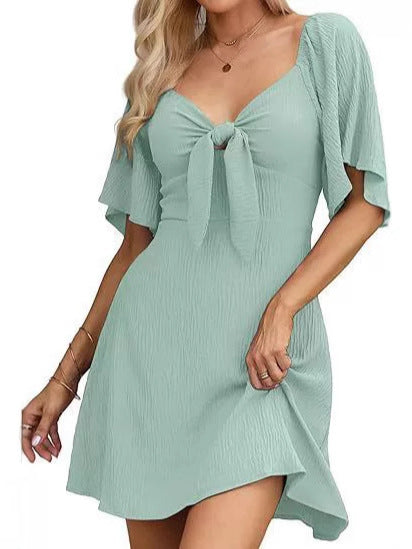 Woman wearing a light green dress with a tie detail on a white background