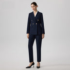 Woman wearing a navy blue suit with gold buttons on a light gray background