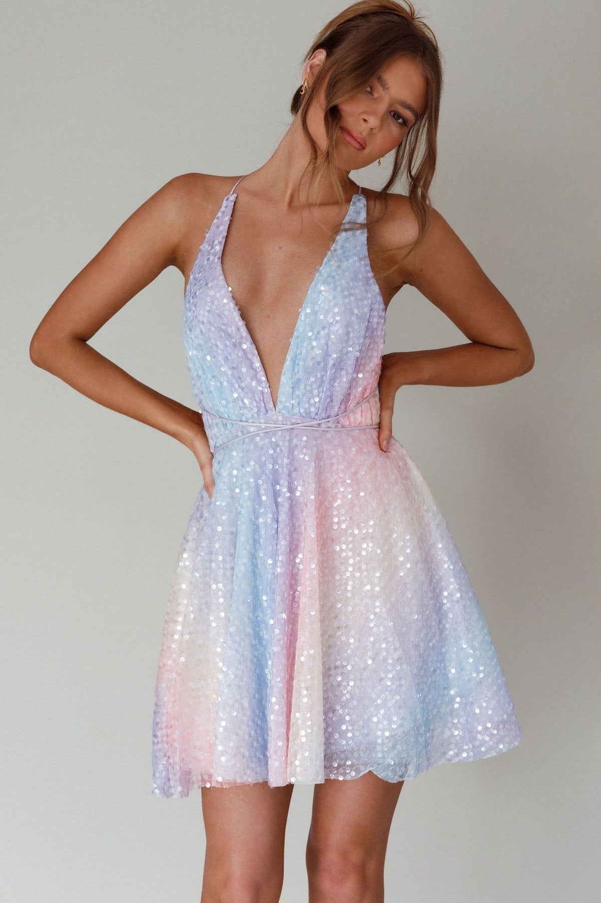 Woman wearing a pastel sequin dress against a plain background
