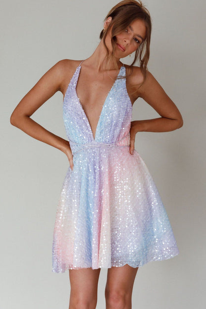 Woman wearing a pastel sequin dress against a plain background