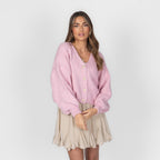 Woman wearing a pink cardigan and beige skirt on a white background