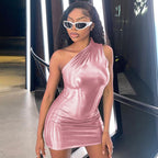 Woman wearing a pink one-shoulder dress and white sunglasses in an indoor setting.