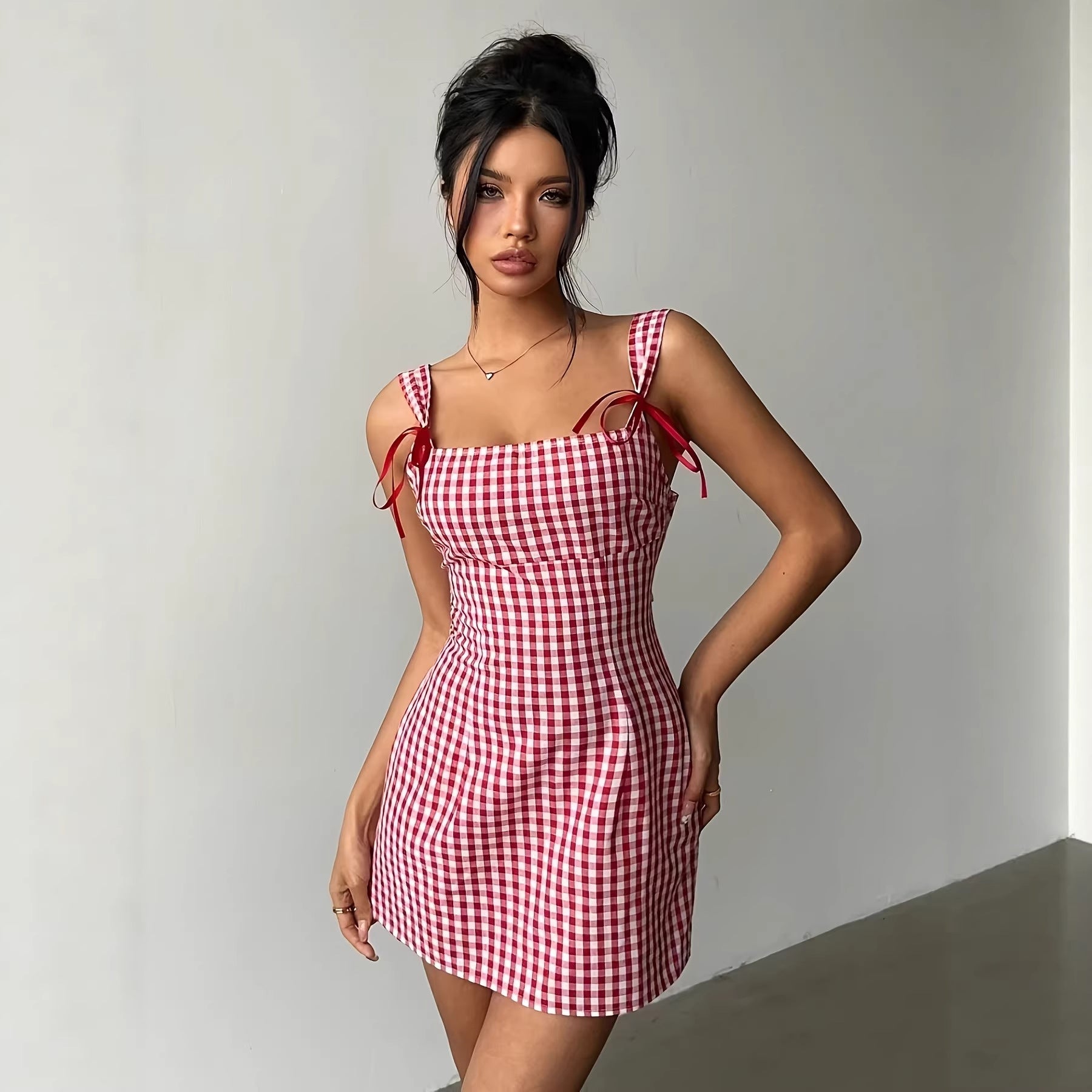 Woman wearing a red and white checkered dress against a plain background
