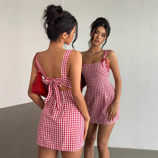 Woman wearing a red and white checkered dress, looking at herself in a mirror.