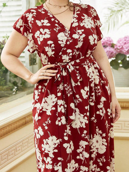 Woman wearing a red floral dress indoors with plants in the background