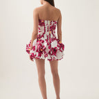 Woman wearing a strapless floral dress on a plain background