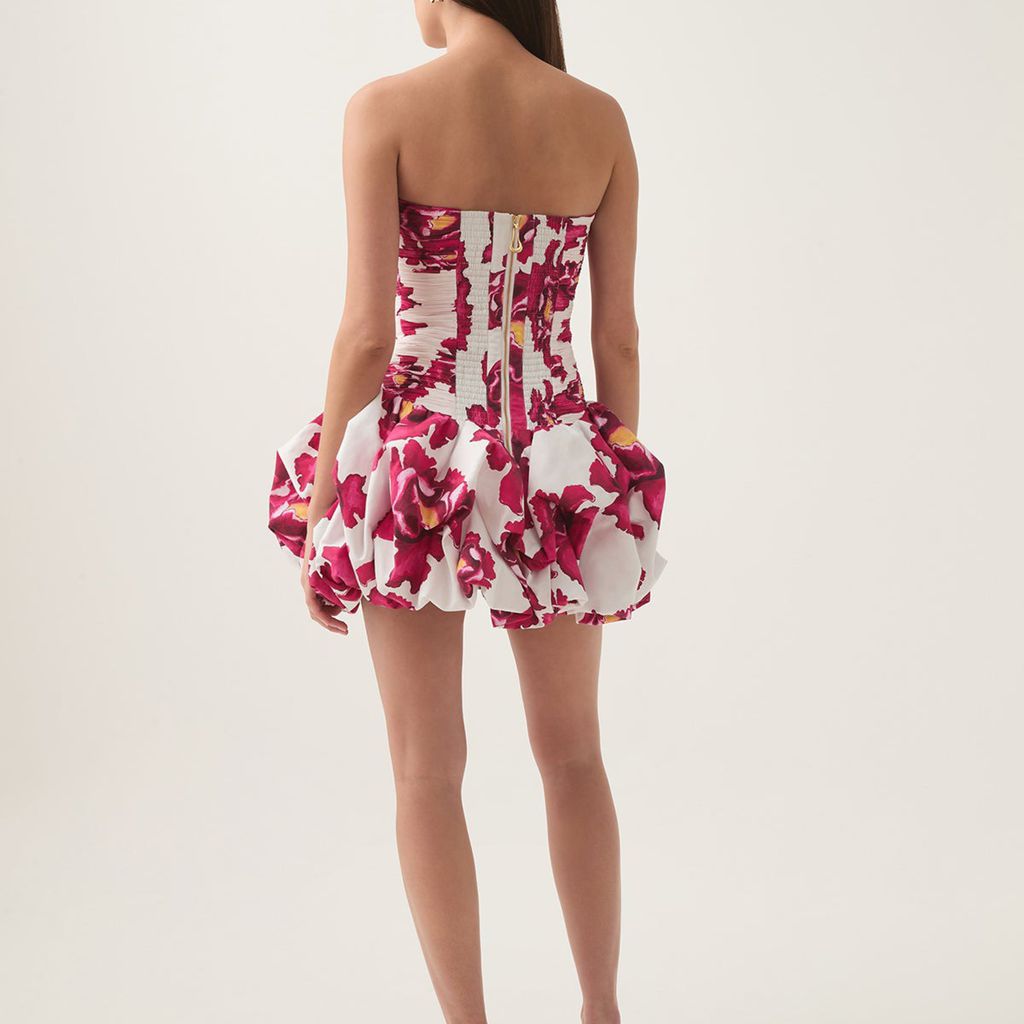 Woman wearing a strapless floral dress on a plain background
