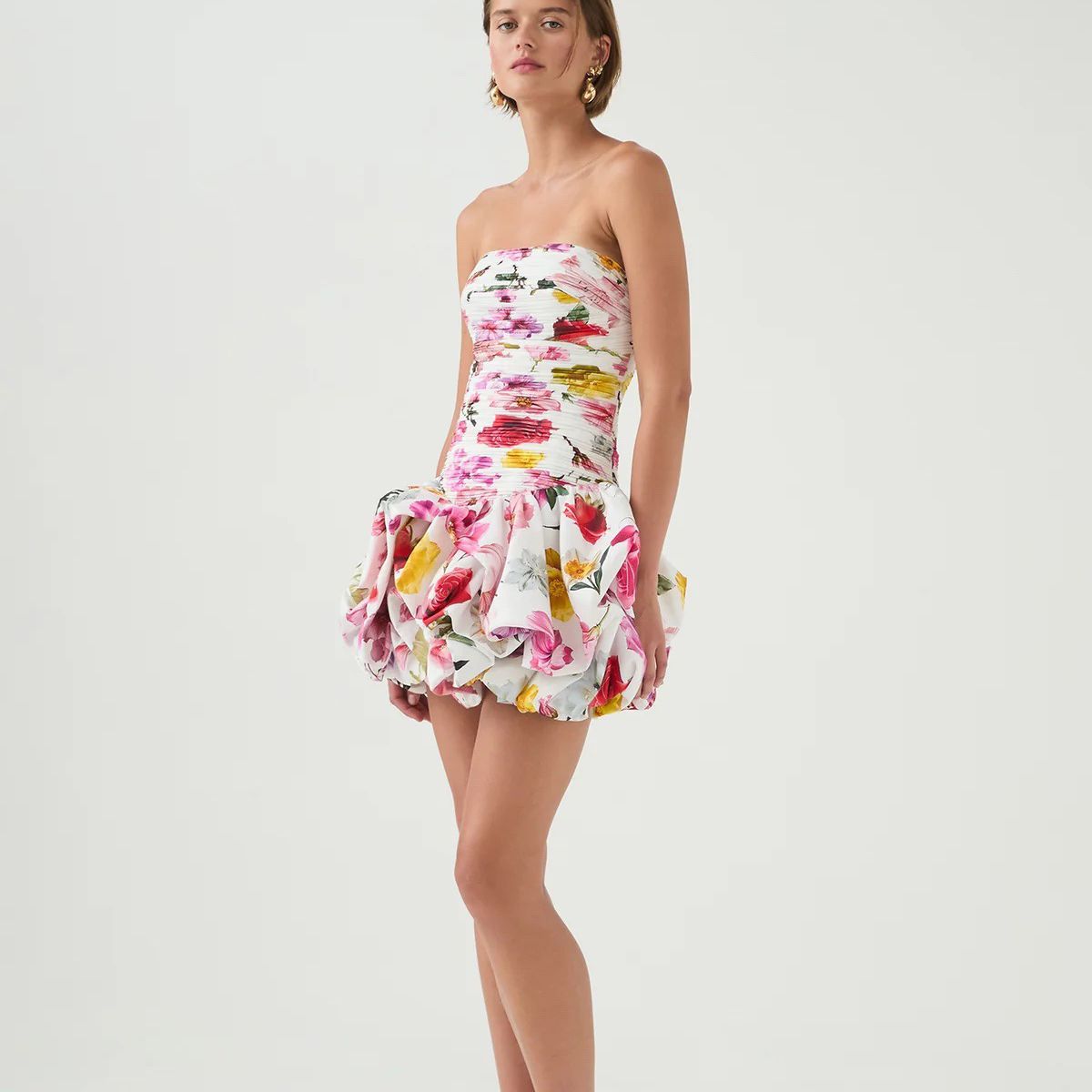 Woman wearing a strapless floral dress on a white background.