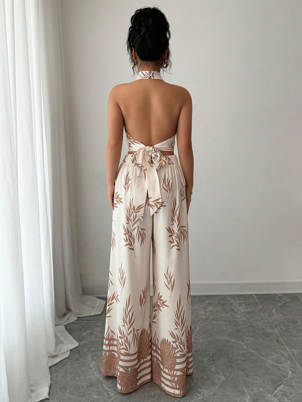 Woman wearing a strapless floral jumpsuit in a minimal indoor setting