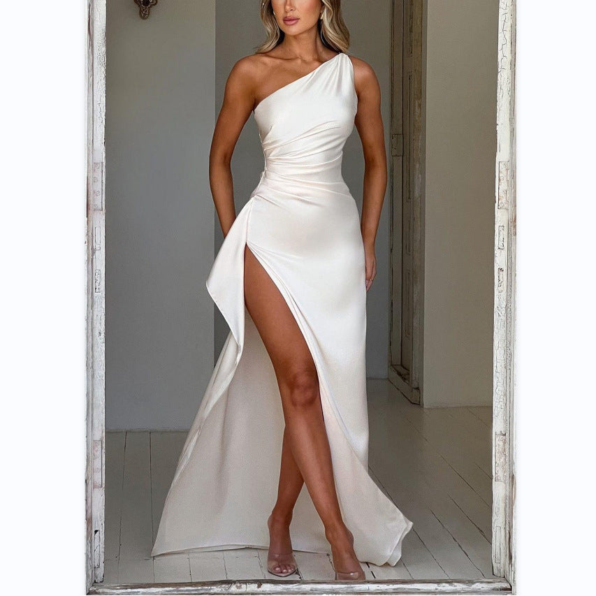 Woman wearing a white one-shoulder dress with a high slit in a neutral setting