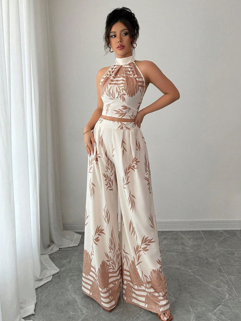 Woman wearing a white outfit with brown floral patterns in a minimalistic room.