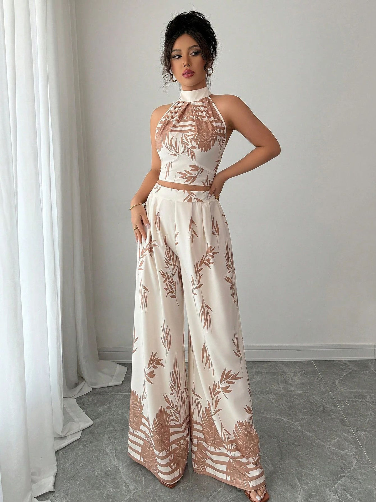 Woman wearing a white outfit with brown floral patterns in a minimalistic room.