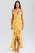 Woman wearing a yellow dress with ruffled details on a white background