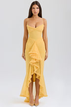 Woman wearing a yellow dress with ruffled details on a white background