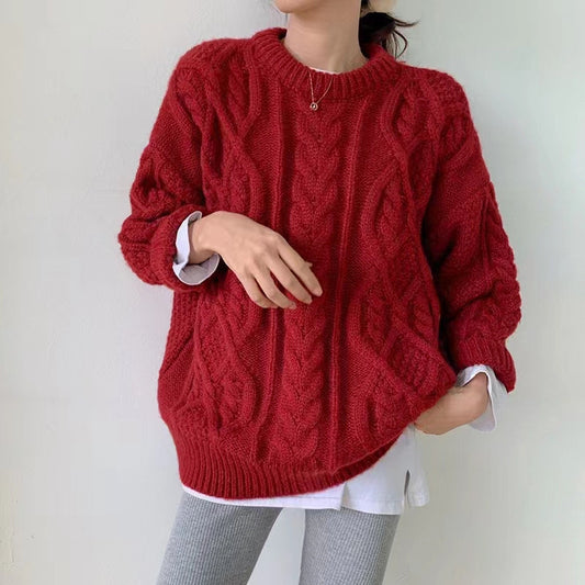 Person wearing a red cable knit sweater against a plain background